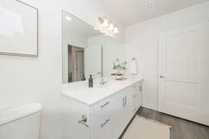 Bathroom with toilet, wood-type flooring, and vanity