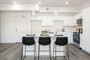 Kitchen featuring decorative light fixtures, appliances with stainless steel finishes, white cabinetry, and a center island