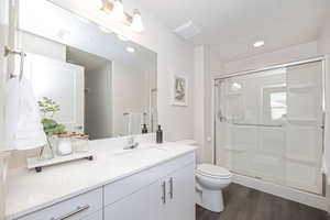 Bathroom with toilet, vanity, wood-type flooring, a textured ceiling, and a shower with door