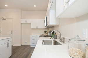 Kitchen with light stone countertops, white cabinets, dark hardwood / wood-style flooring, sink, and stove