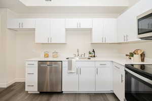 Kitchen featuring sink, white cabinetry, and appliances with stainless steel finishes