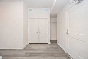 Hall with a textured ceiling and light hardwood / wood-style flooring