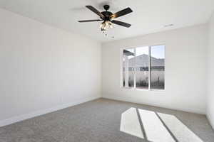 Carpeted spare room featuring ceiling fan