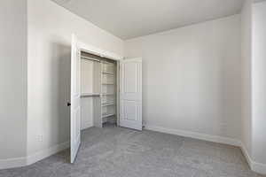 Unfurnished bedroom with light carpet and a closet