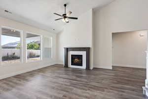 Unfurnished living room featuring ceiling fan, a fireplace, dark wood-type flooring, a textured ceiling, and high vaulted ceiling