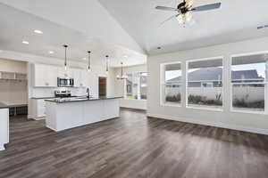 Kitchen with decorative light fixtures, tasteful backsplash, white cabinetry, an island with sink, and stainless steel appliances