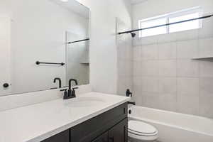 Full bathroom with toilet, vanity, and tiled shower / bath