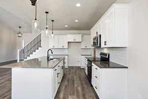 Kitchen with an island with sink, appliances with stainless steel finishes, sink, and white cabinetry