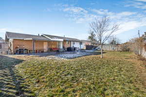 Rear view of fully fenced property with a playground, a lawn, and a patio area