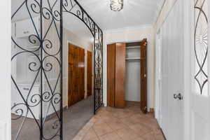 Corridor featuring light carpet, crown molding, and a textured ceiling