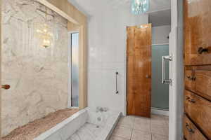 Primary Bathroom featuring tile patterned floors, a bathing tub, and a chandelier