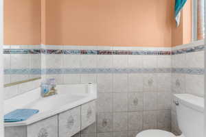 Bathroom featuring toilet, tile walls, and a bathtub