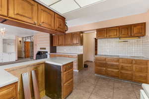 Kitchen with tasteful backsplash, light tile patterned flooring, and a chandelier