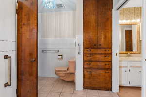 Primary Bathroom featuring tile walls, tile patterned floors, vanity, and toilet