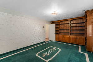 Interior space featuring built in shelves, ornamental molding, and a textured ceiling