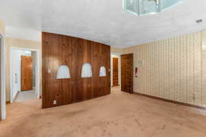 Carpeted Primary bedroom with a textured ceiling and wooden walls