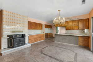 Kitchen featuring decorative backsplash, sink, hanging light fixtures, light tile patterned floors, and a chandelier