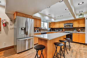 Kitchen featuring a kitchen bar, stainless steel appliances, tasteful backsplash, a kitchen island, and sink