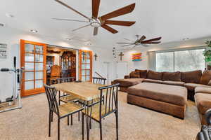 Sunroom featuring a ceiling fan and light colored carpet