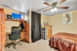 Bedroom featuring ceiling fan, light carpet, and a textured ceiling