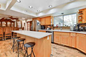 Kitchen featuring appliances with stainless steel finishes, a kitchen island, a kitchen bar, sink, and ceiling fan