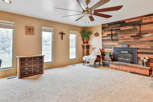 Living room featuring ceiling fan, carpet, and wood mantle