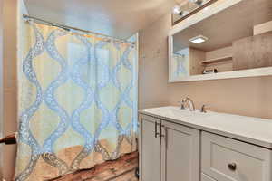 Bathroom with a textured ceiling, hardwood / wood-style flooring, and vanity