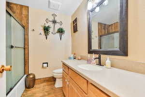 Full bathroom featuring enclosed tub / shower combo, wood-type flooring, toilet, and vanity