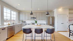 Kitchen featuring pendant lighting, a kitchen island, sink, light stone countertops, and stainless steel appliances