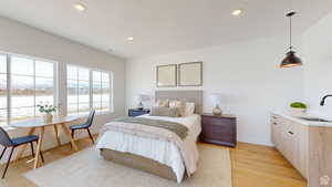 Bedroom featuring light wood-type flooring, a water view, and sink