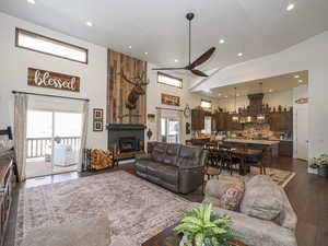 Living room featuring dark hardwood / wood-style floors, a large fireplace, a high ceiling, and ceiling fan