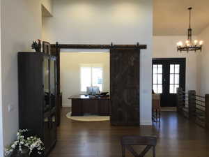 Interior space featuring a chandelier, a barn door, dark wood-style flooring, baseboards, and french doors