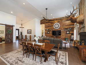 Dining room with lofted ceiling, a barn door, dark hardwood / wood-style floors, and wooden walls