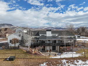 Snow covered property featuring a patio area, a deck with mountain view, and a lawn