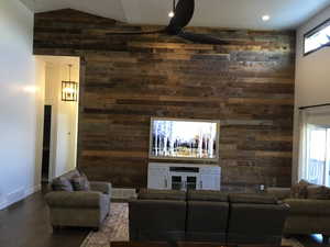 Living area with wood walls, ceiling fan, visible vents, and dark wood-type flooring