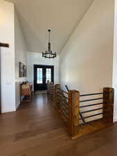 Foyer entrance with high vaulted ceiling, french doors, wood-type flooring, and a notable chandelier