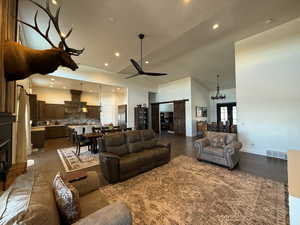 Living room featuring high vaulted ceiling, a barn door, visible vents, a ceiling fan, and dark wood finished floors