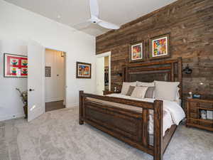 Bedroom featuring light carpet, ceiling fan, and wooden walls