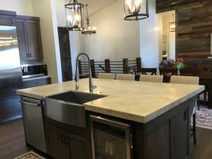 Kitchen featuring wine cooler, stainless steel appliances, light countertops, a chandelier, and a sink