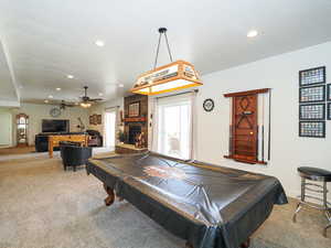 Rec room with carpet, ceiling fan, pool table, and a stone fireplace