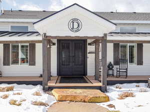 Snow covered property entrance featuring a porch