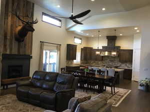 Living room featuring dark wood-type flooring, a wealth of natural light, a large fireplace, and a high ceiling