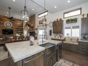 Kitchen with sink, a wealth of natural light, stainless steel dishwasher, and an island with sink