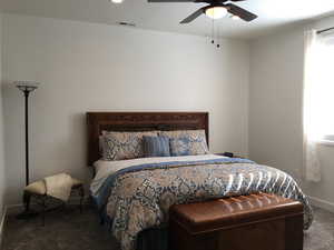 Carpeted bedroom featuring a ceiling fan, visible vents, and baseboards