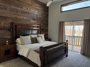 Carpeted bedroom featuring access to exterior and wood walls