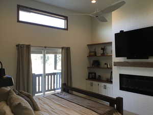 Bedroom featuring access to exterior, a fireplace, and a ceiling fan