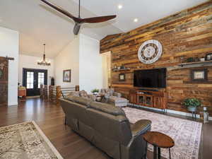 Living room with high vaulted ceiling, dark wood-type flooring, wood walls, and french doors