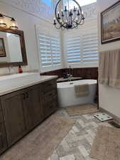 Bathroom featuring a chandelier, visible vents, vanity, a freestanding bath, and wainscoting