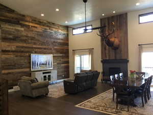 Dining room featuring wood walls, a fireplace, wood finished floors, and a towering ceiling