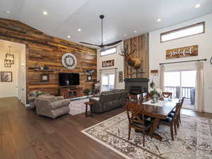 Dining area with ceiling fan, a wealth of natural light, wooden walls, and hardwood / wood-style flooring